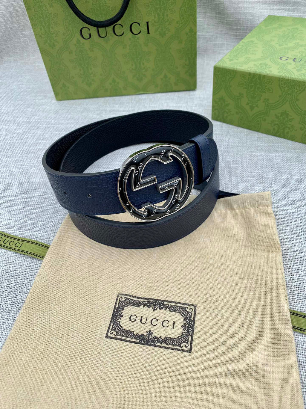 Navy blue leather belt with round double-G logo buckle on beige pouch