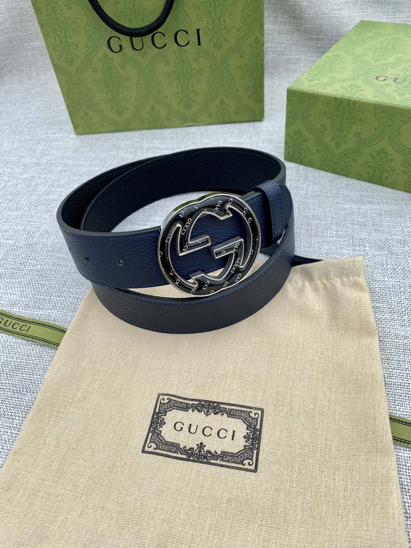 Navy blue leather belt with round double-G logo buckle on beige pouch