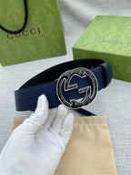 Navy blue leather belt with round double-G logo buckle, gloved hand