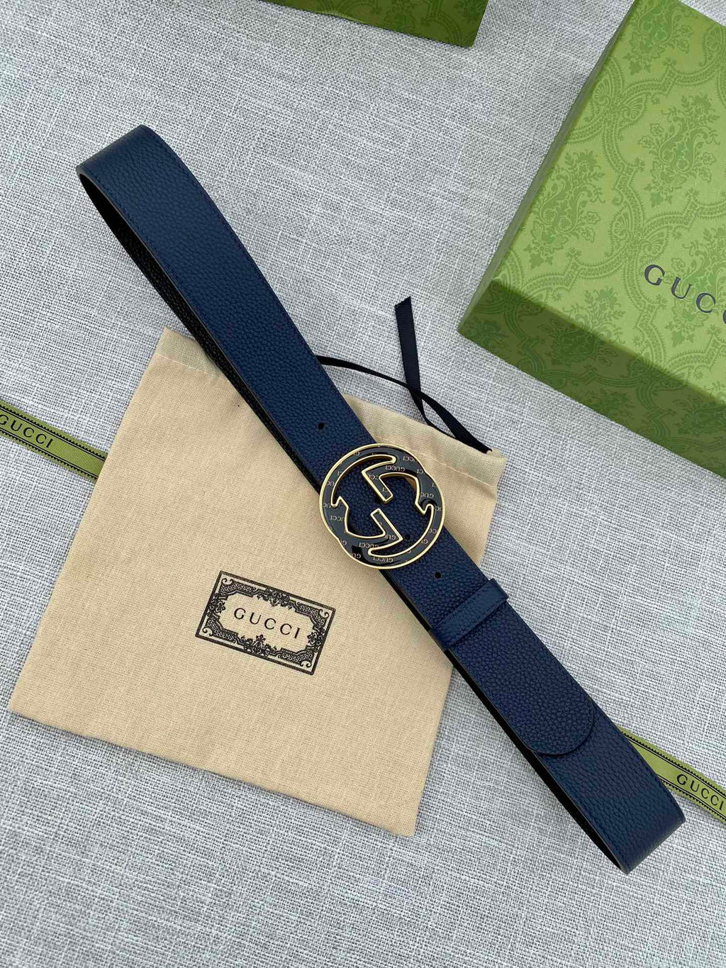 Navy blue leather belt laid flat with round double-G logo buckle
