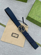 Navy blue leather belt laid flat with round double-G logo buckle