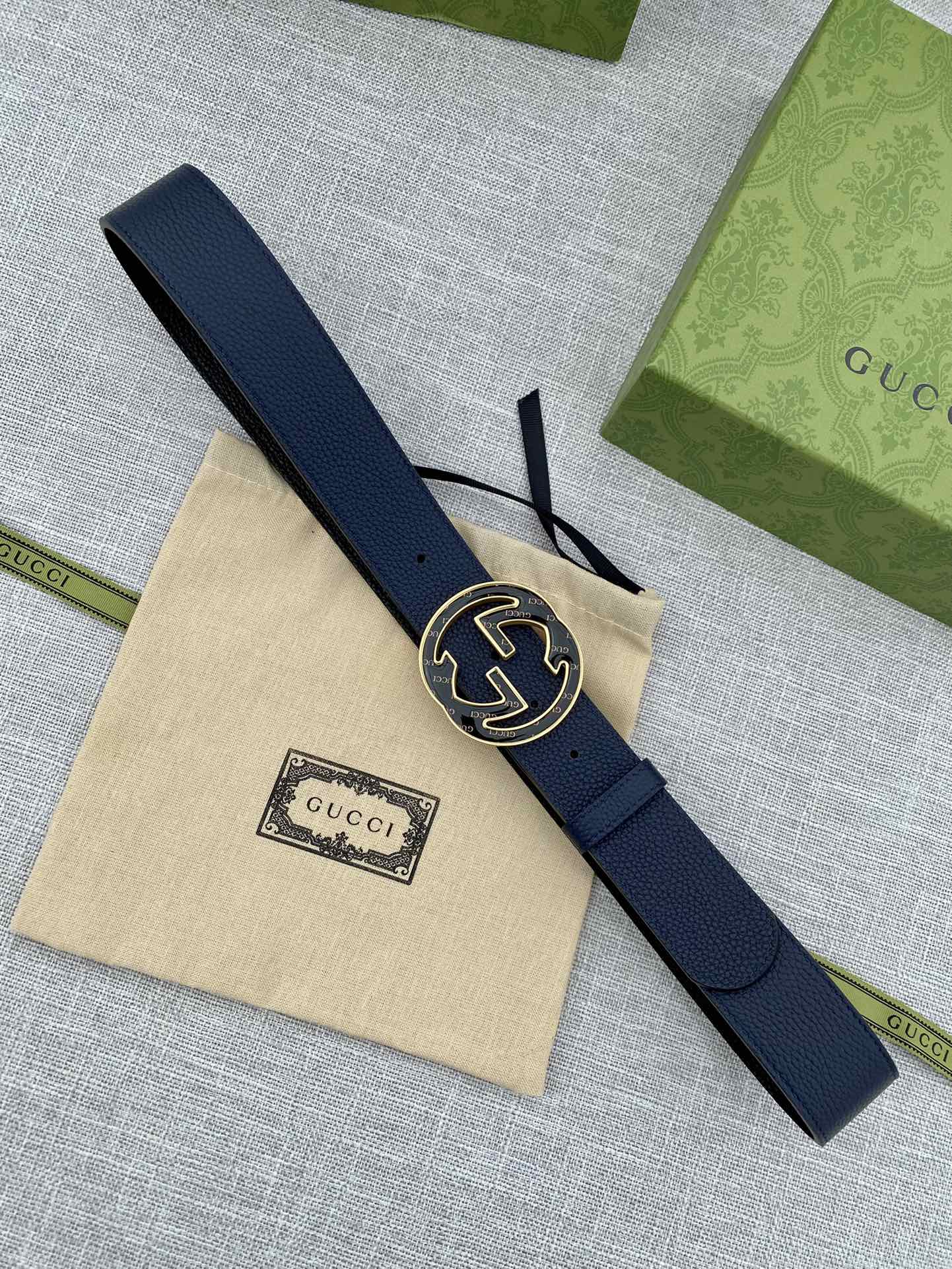 Navy blue leather belt laid flat with round double-G logo buckle