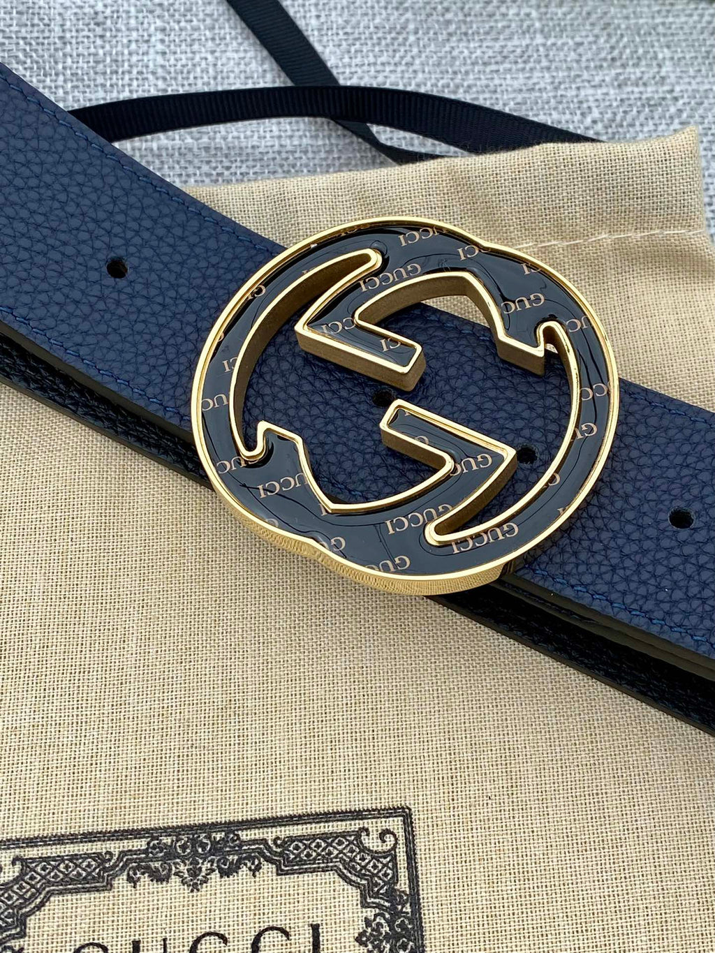 Close-up of navy blue leather belt and round double-G buckle