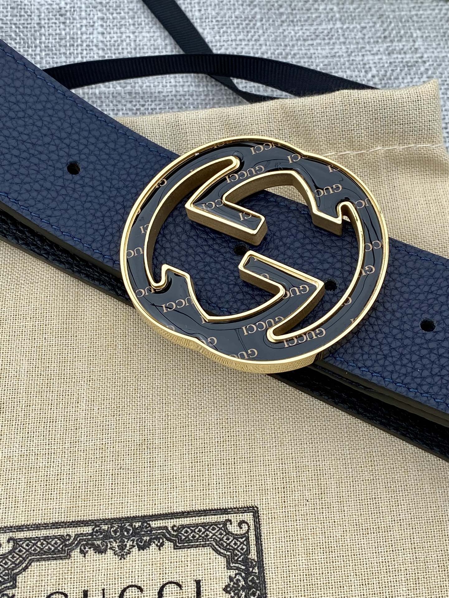 Close-up of navy blue leather belt and round double-G buckle