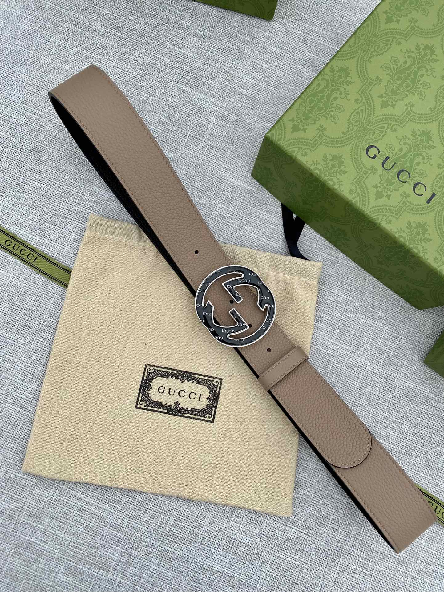 Tan leather belt with round GG logo buckle on end and punched sizing holes