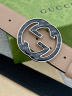 Close-up of tan leather belt with circular GG logo buckle in metal frame