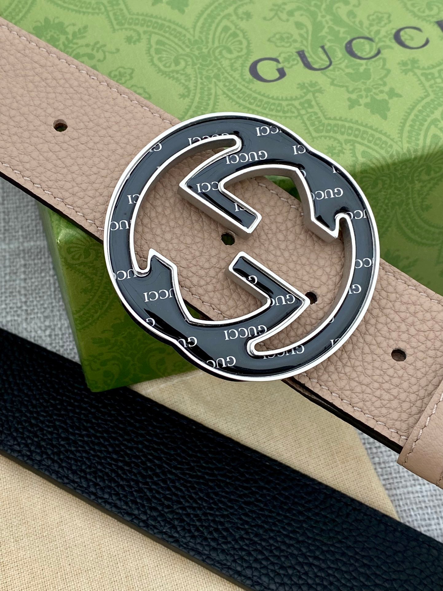Close-up of tan leather belt with circular GG logo buckle in metal frame