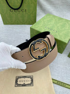 Tan leather belt with round GG logo buckle held with white glove