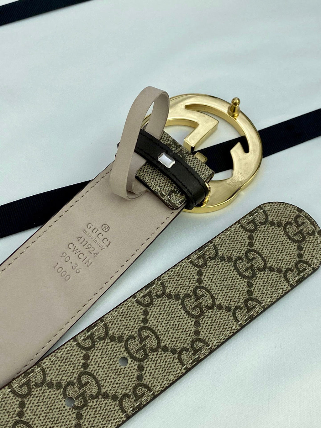 GG canvas belt with gold-tone metal buckle and beige keeper strap; close-up hardware.
