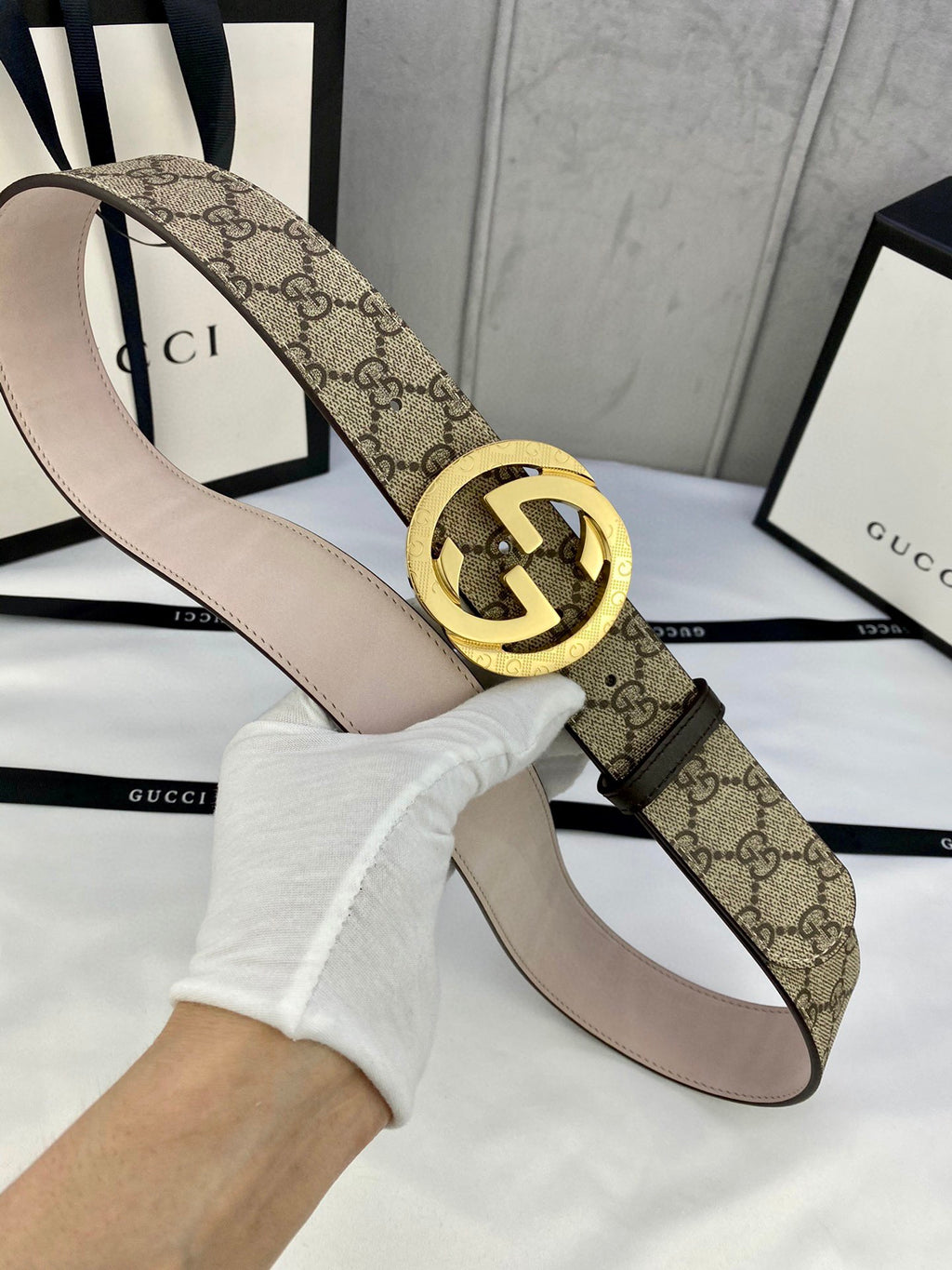 GG canvas belt with gold-tone double G buckle and light beige leather underside; angled view.