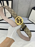 GG canvas belt with gold-tone double G buckle and light beige leather underside; angled view.