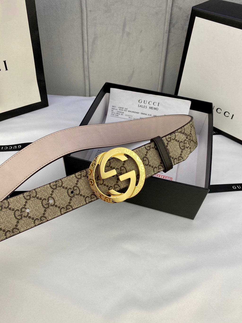 GG canvas belt with gold-tone double G buckle, beige leather lining and visible strap holes.