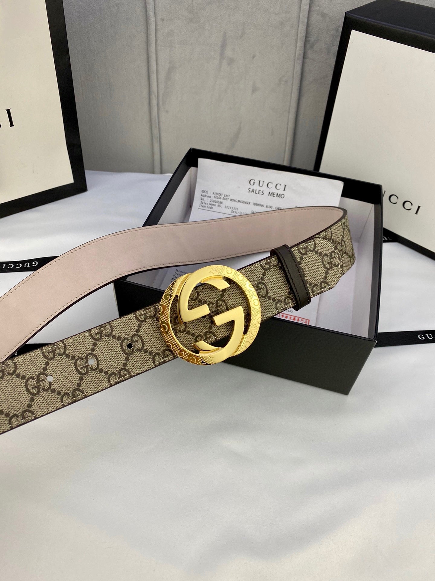 GG canvas belt with gold-tone double G buckle, beige leather lining and visible strap holes.