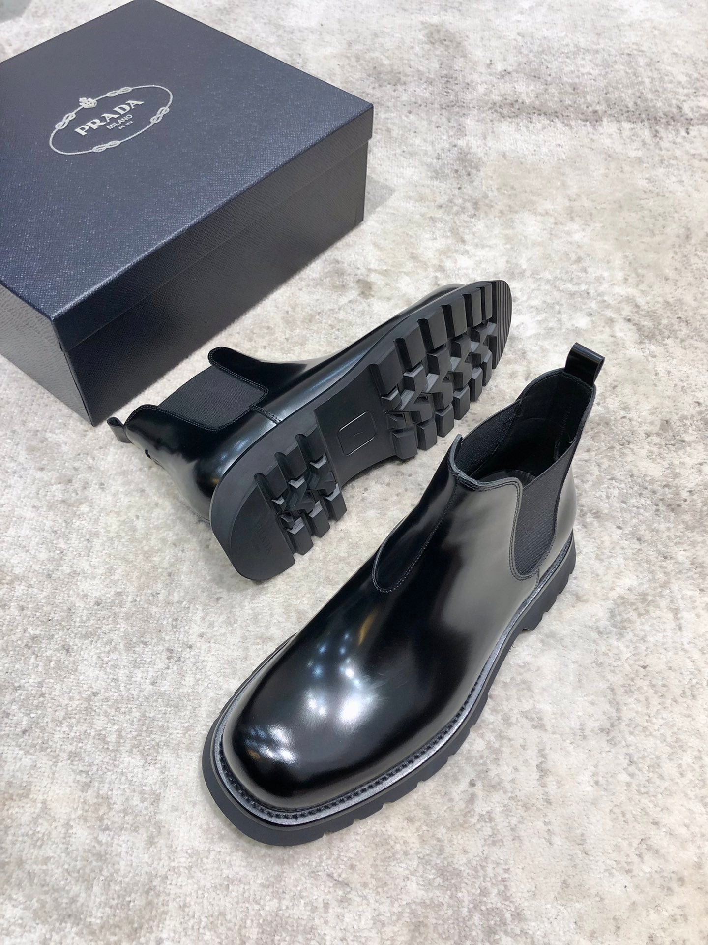 Prada unisex Chelsea boots in dark glossy leather with lug outsole and elastic ankle gore