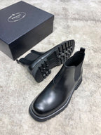 Black leather Chelsea boots showing side profile and rugged treaded rubber outsole
