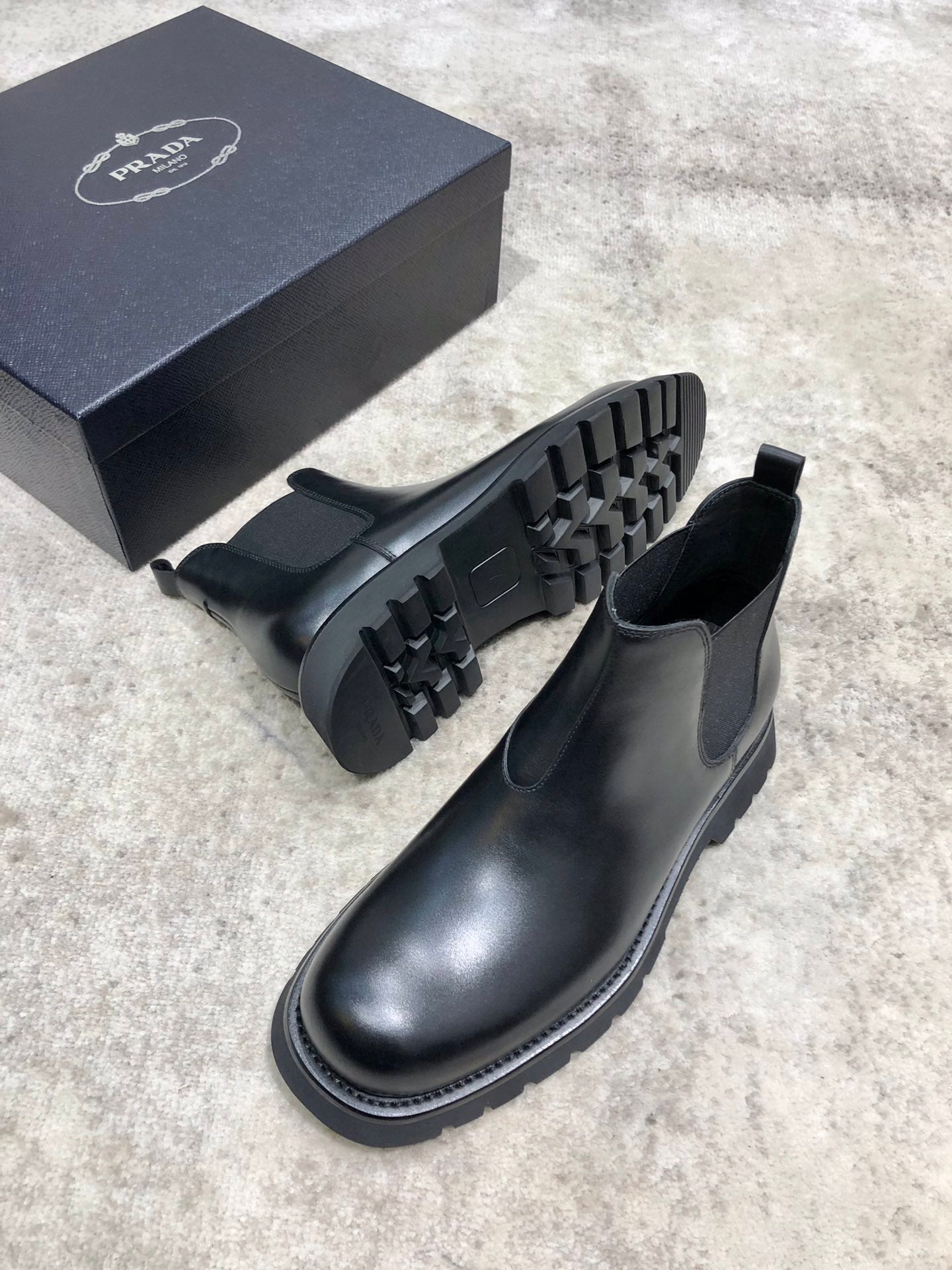 Black leather Chelsea boots showing side profile and rugged treaded rubber outsole