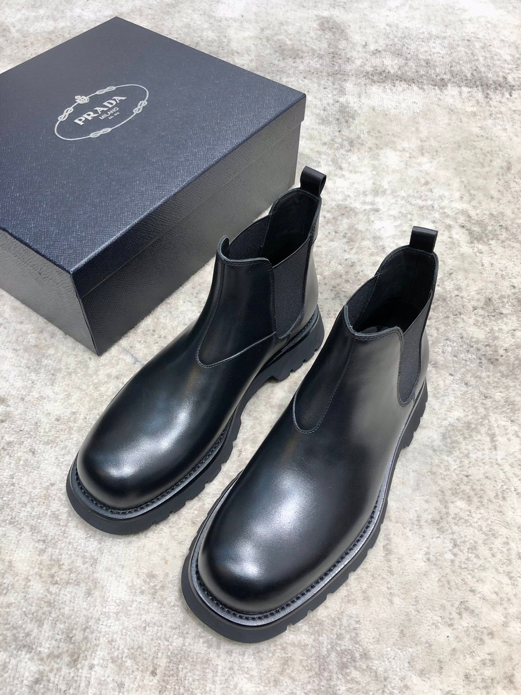 Pair of black leather Chelsea boots with rounded toe, elastic sides, and tread sole