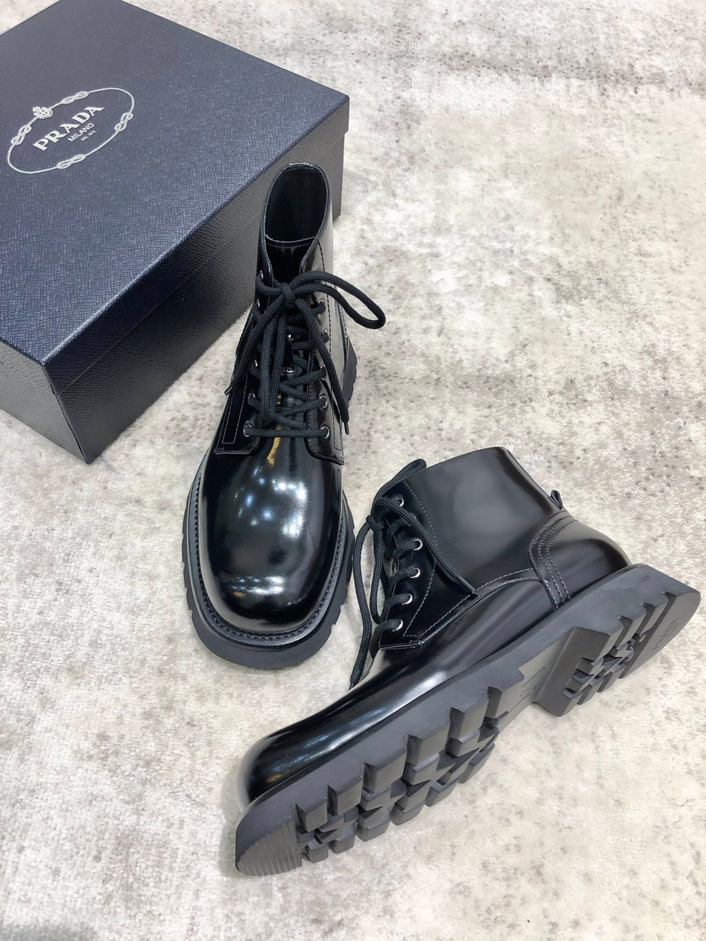 Ankle lace-up leather boots, glossy dark upper, side view of chunky tread sole