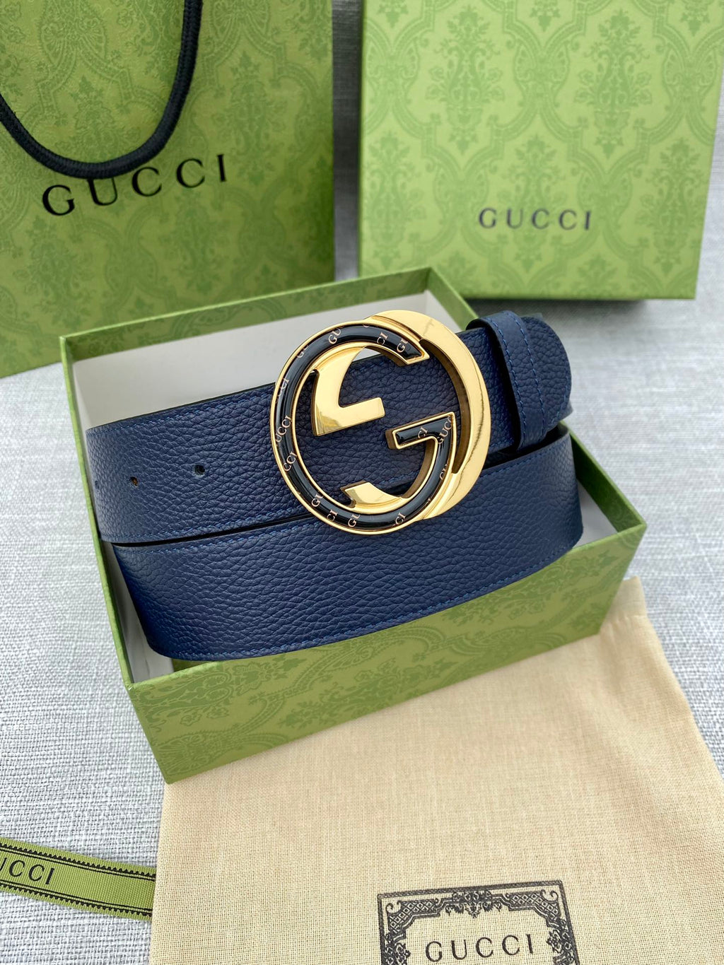 Gucci leather belt with navy strap and gold-tone logo buckle on gift box