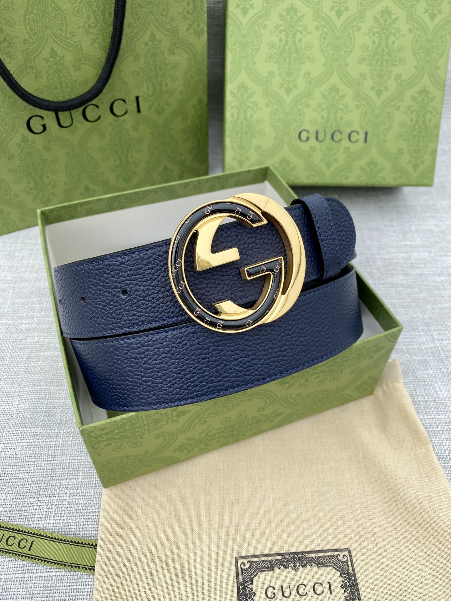 Gucci leather belt with navy strap and gold-tone logo buckle on gift box