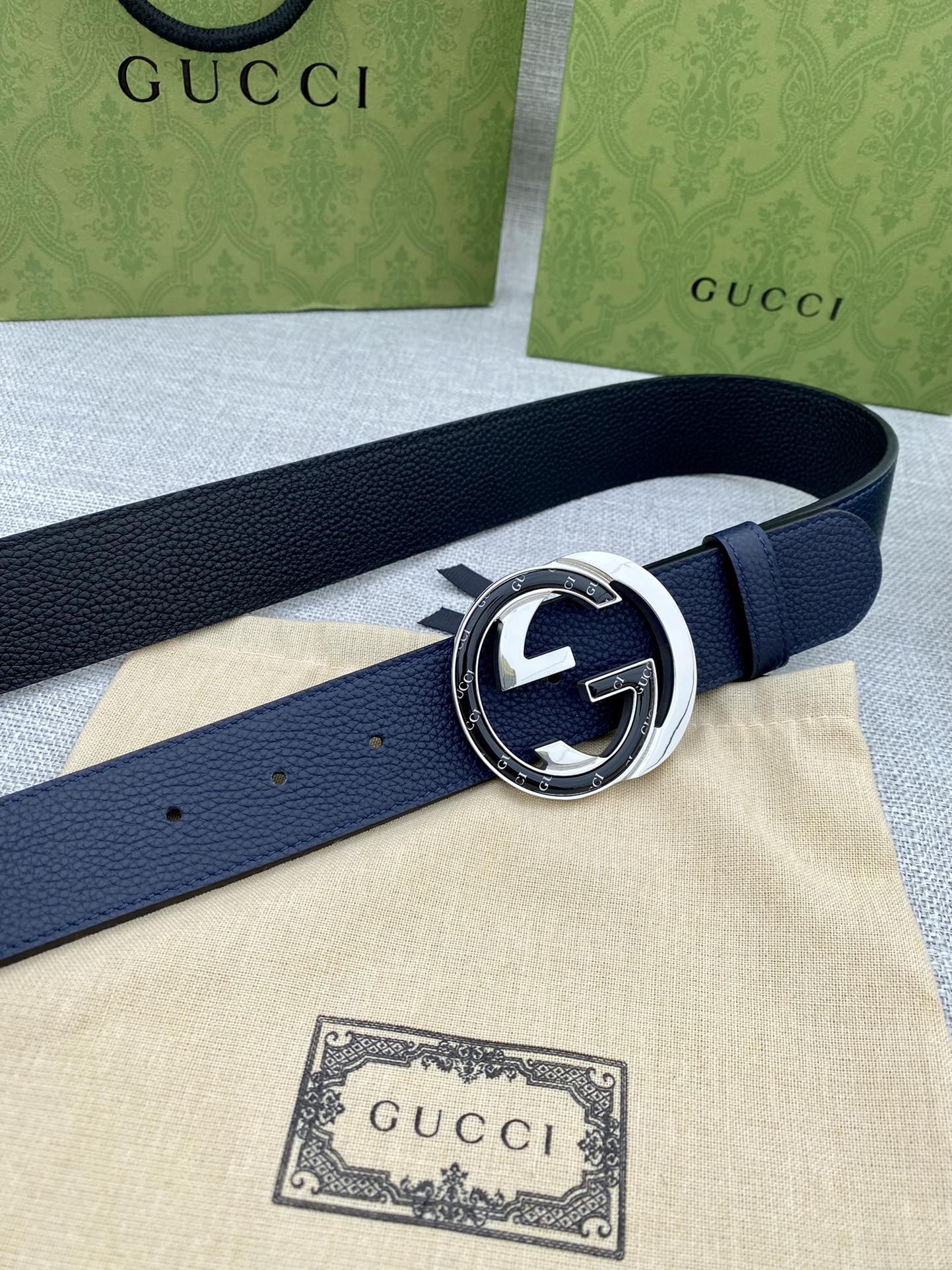Navy leather belt with round silver-tone buckle and interlocking G emblem