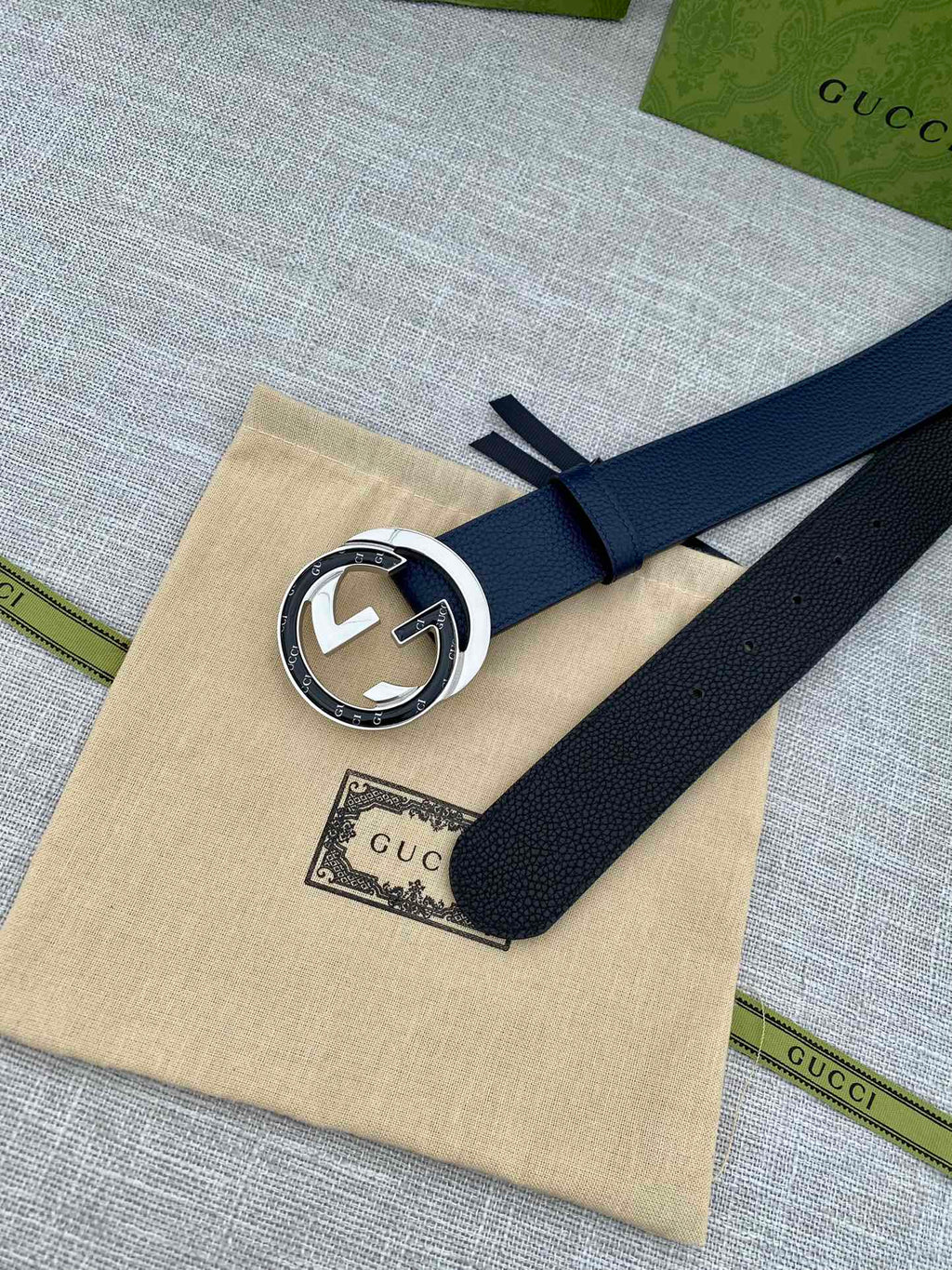 Navy leather belt with round G buckle on beige dust bag