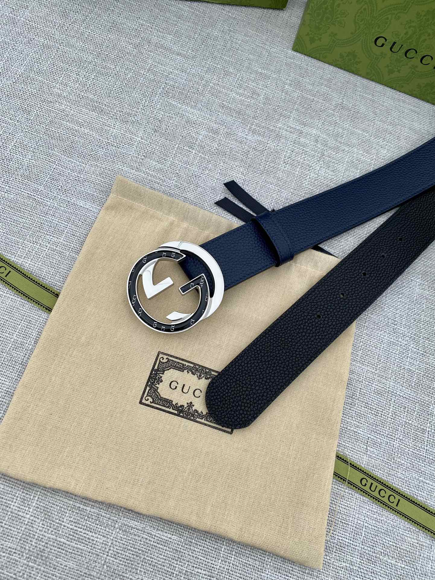 Navy leather belt with round G buckle on beige dust bag