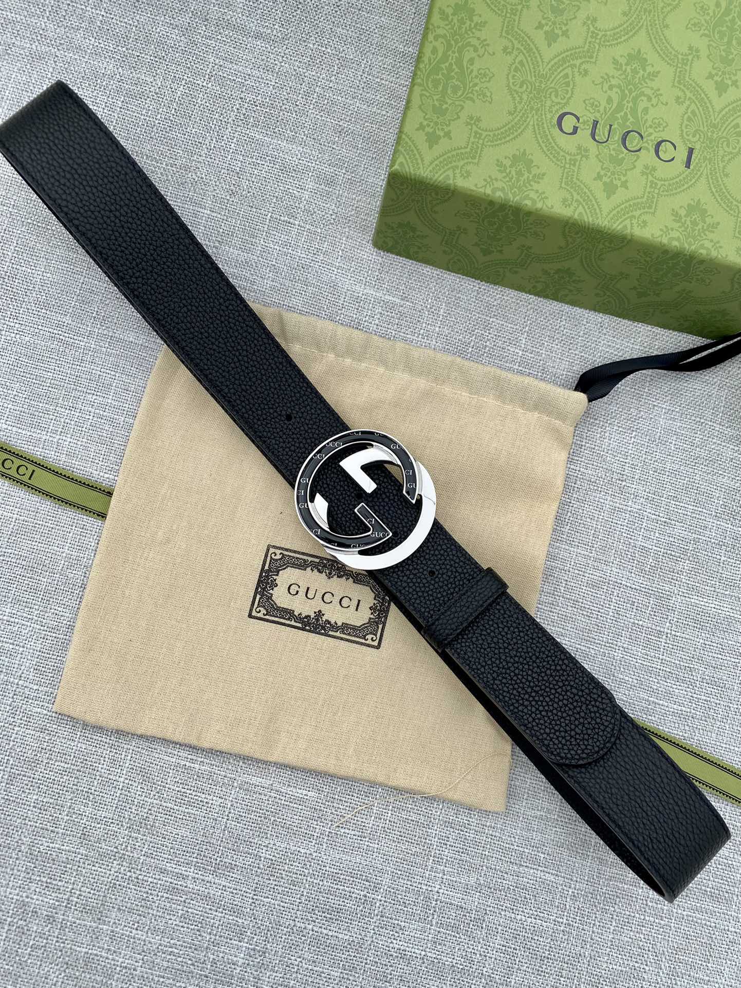 Gucci belt with black leather strap and dark enamel GG buckle, gold rim