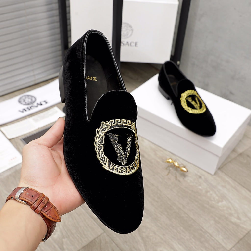Versace black loafer held in hand, gold embroidered crest on vamp
