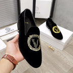 Versace black loafer held in hand, gold embroidered crest on vamp