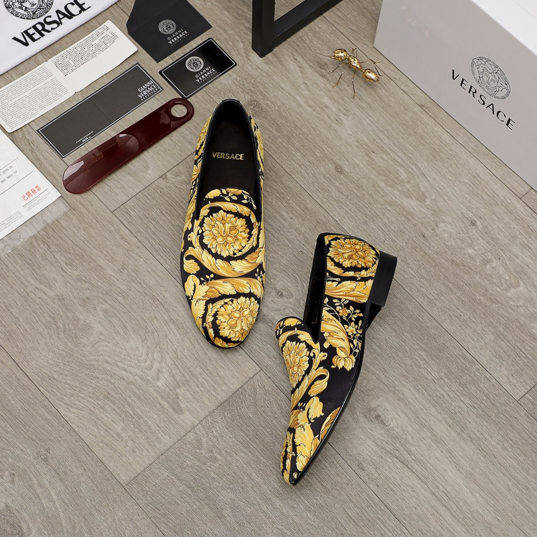 Luxury slip-on shoes with black upper and gold baroque motif, low slim heel, pair
