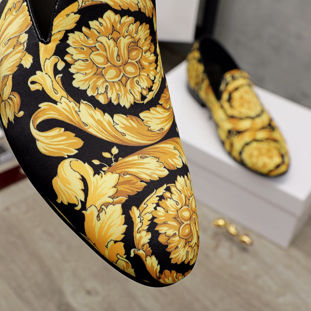 Luxury slip-on shoes close-up: gold floral and scroll pattern on black fabric
