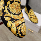 Luxury slip-on shoes close-up: gold floral and scroll pattern on black fabric
