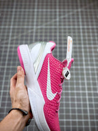 Pink basketball sneaker with white swoosh and textured upper, heel and side view