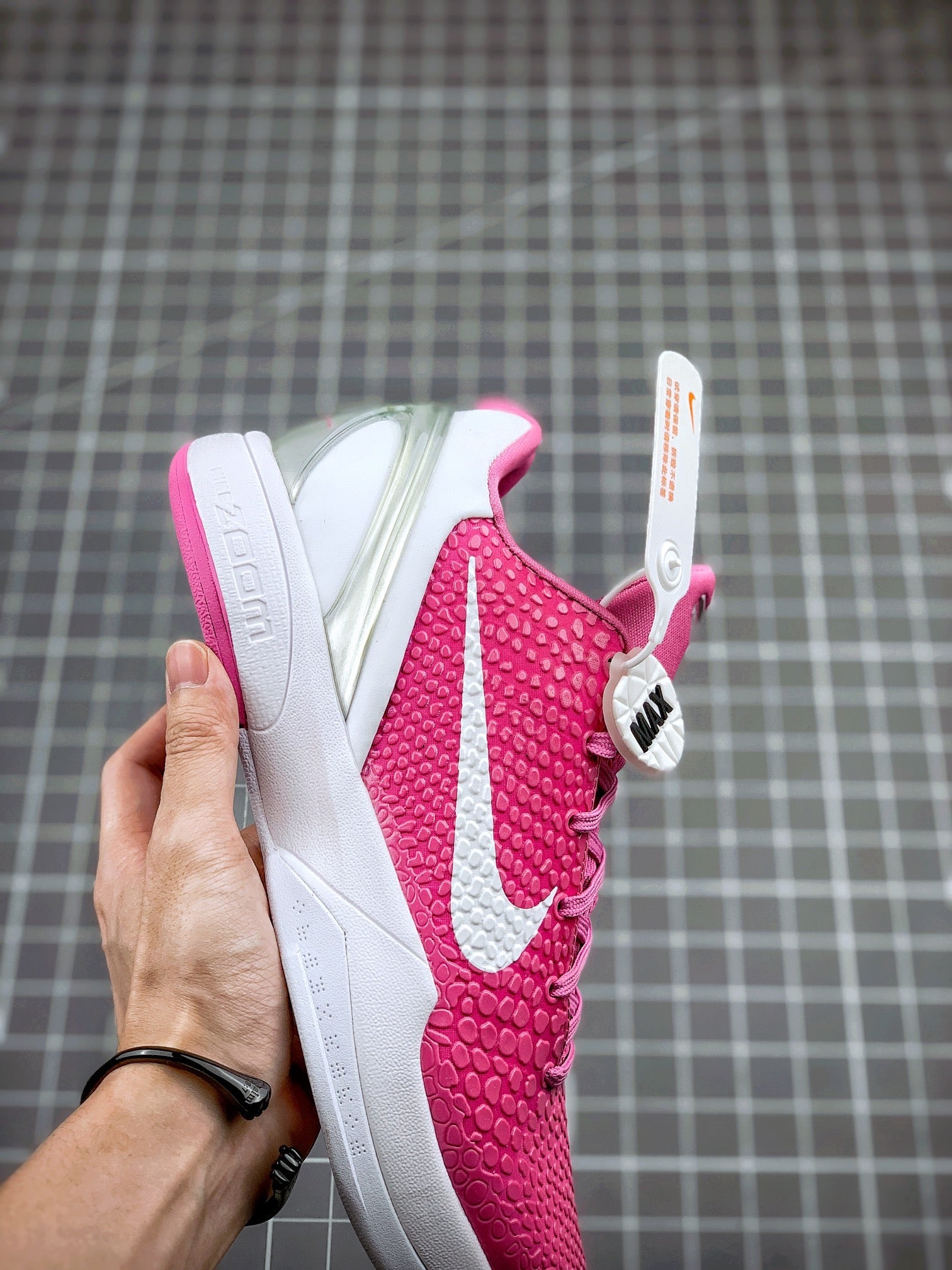 Pink basketball sneaker with white swoosh and textured upper, heel and side view