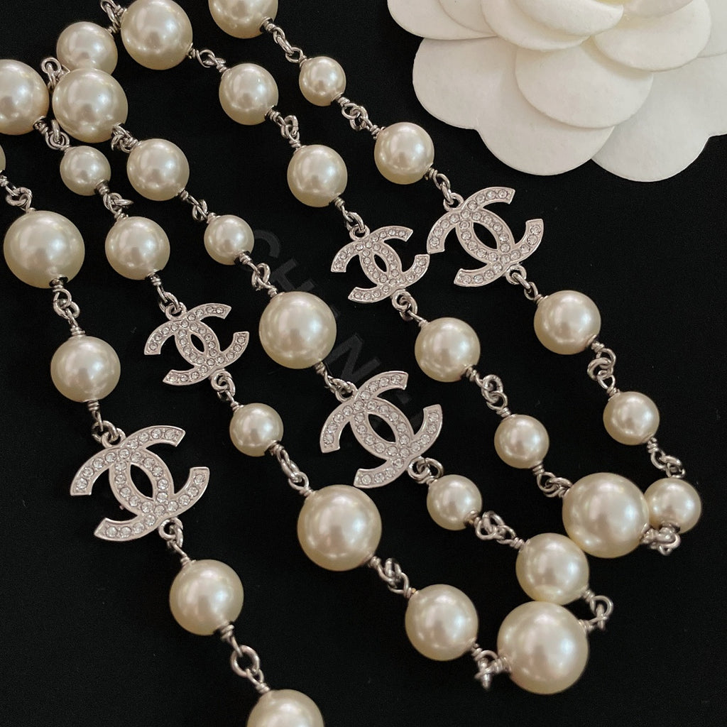 Close-up of pearl bead necklace with silver-tone chain and CC logo charms