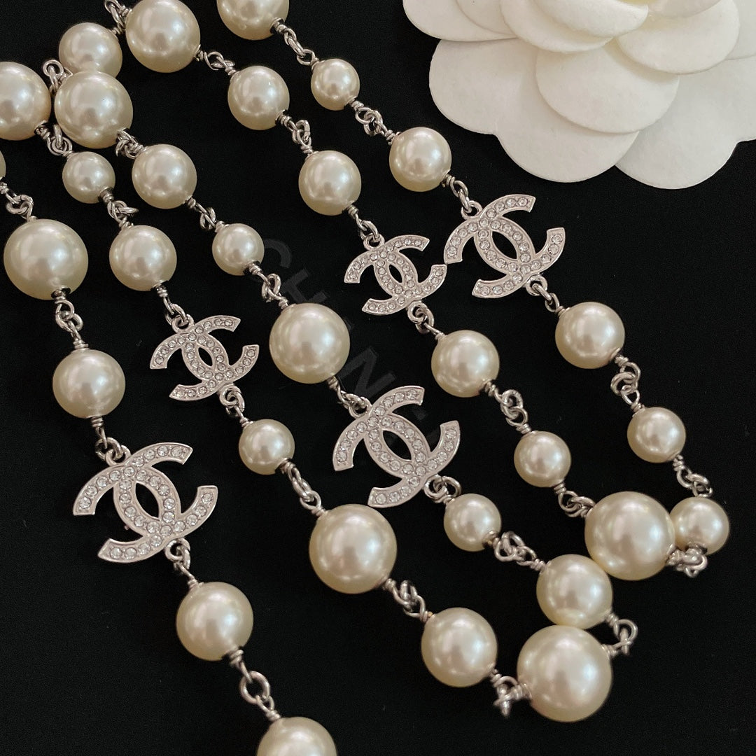 Close-up of pearl bead necklace with silver-tone chain and CC logo charms