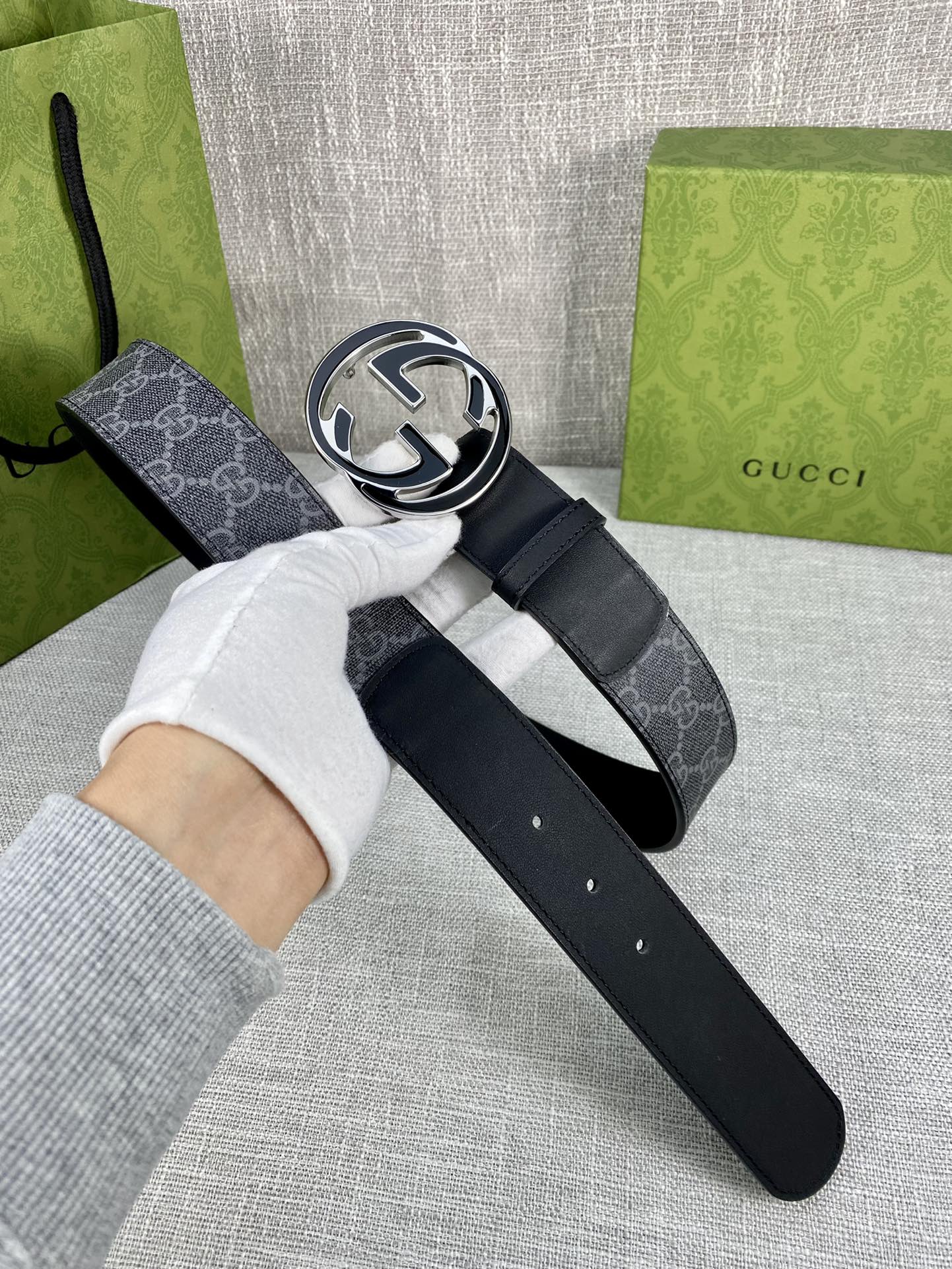 Gucci belt with dark monogram strap and silver-tone double G buckle, on dark leather