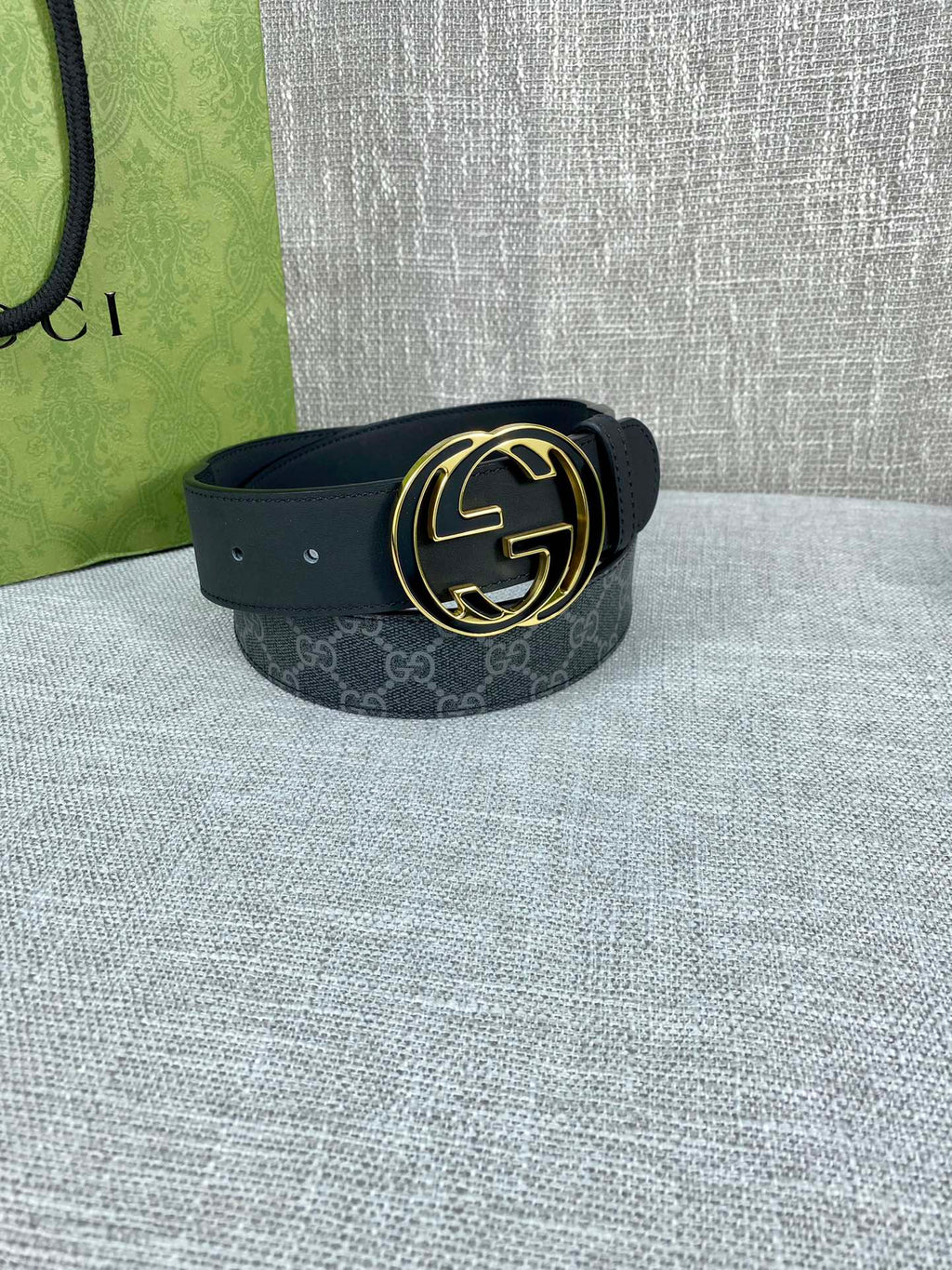Gucci belt with dark strap and gold-tone double G buckle, curved round face