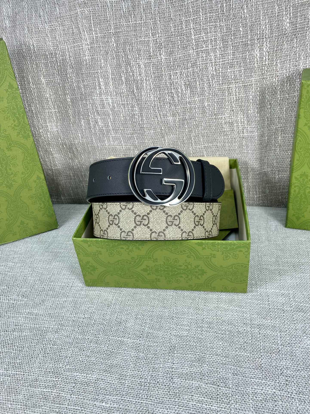 Gucci belt with dark strap and round GG logo buckle centered on the belt