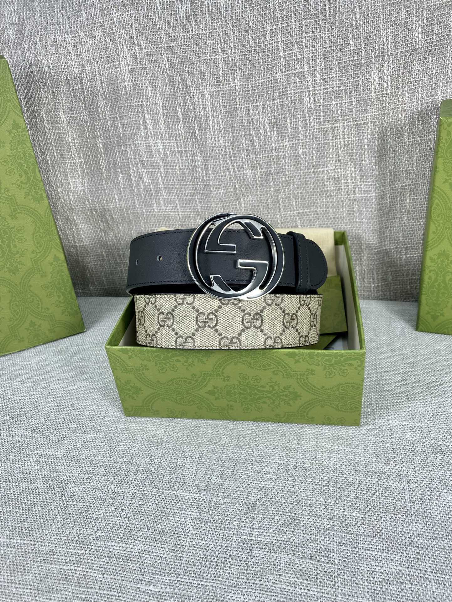 Gucci belt with dark strap and round GG logo buckle centered on the belt