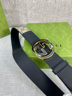 Gucci belt with dark strap and round GG logo buckle, patterned canvas panel visible