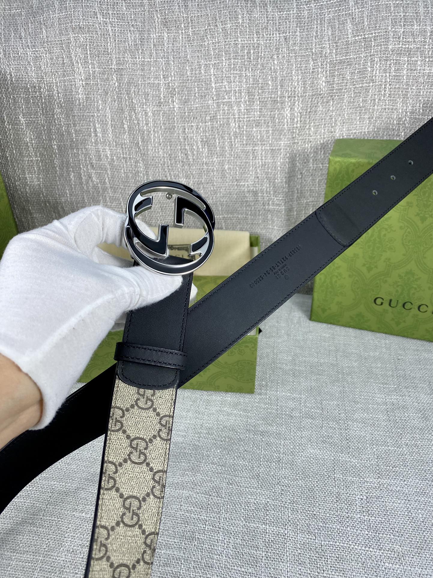 Gucci belt buckle close-up: round GG logo in black and silver on dark strap