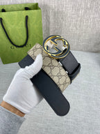 Gucci belt with dark strap and round GG logo buckle, held by gloved hand