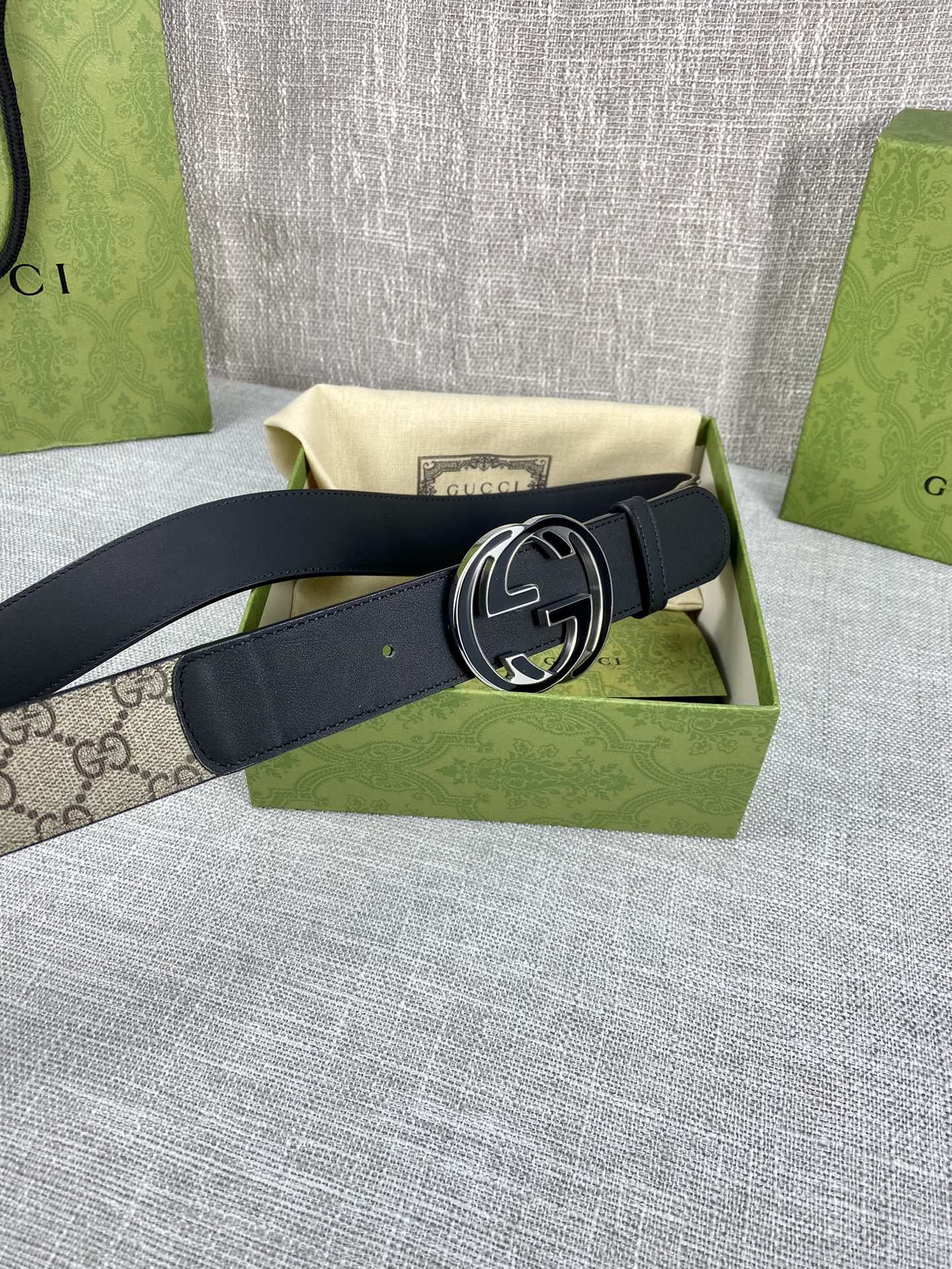 Gucci belt with dark strap and round GG logo buckle, belt end folded