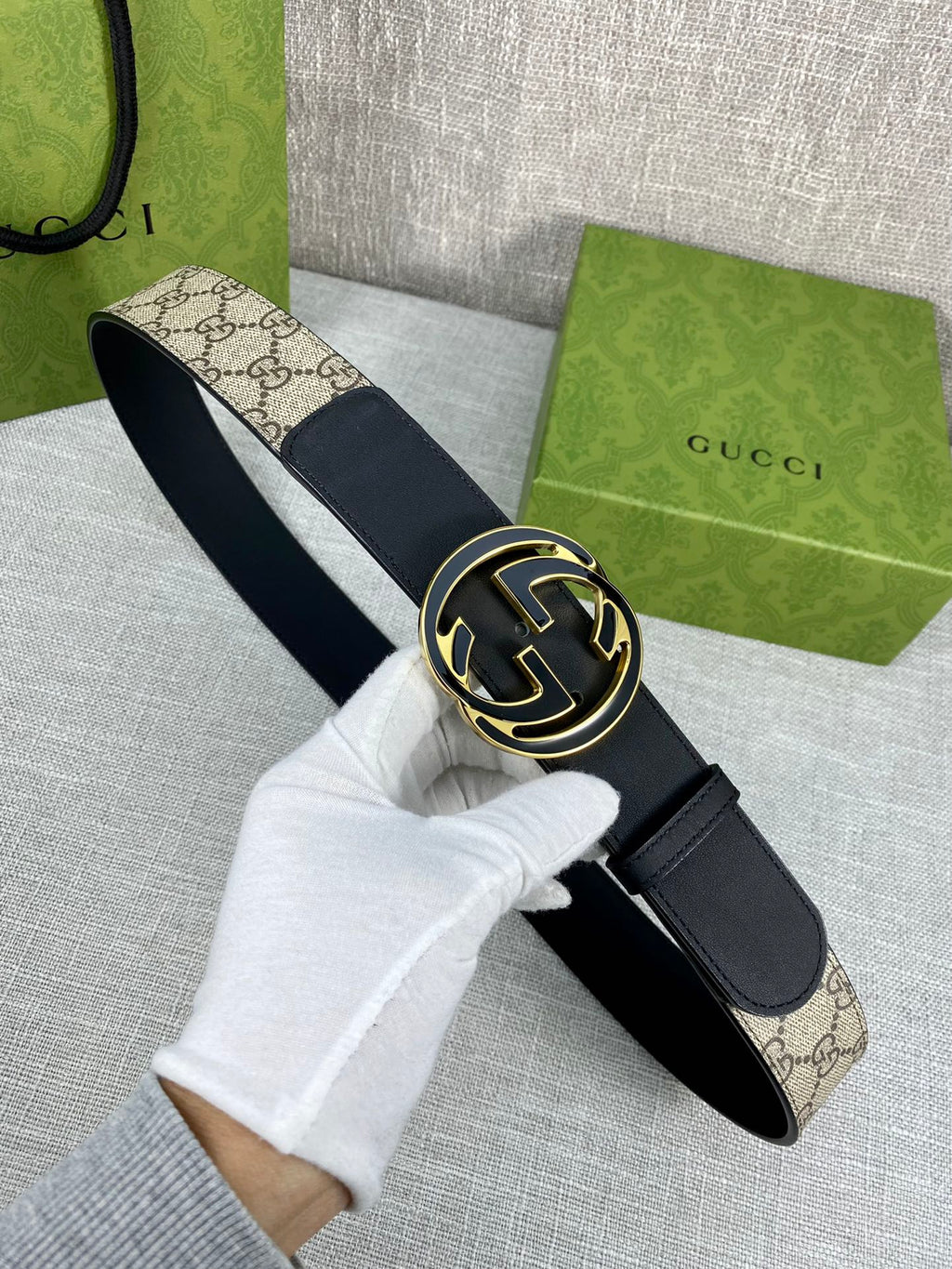 Gucci belt with dark strap and round GG logo buckle, worn end and clasp shown