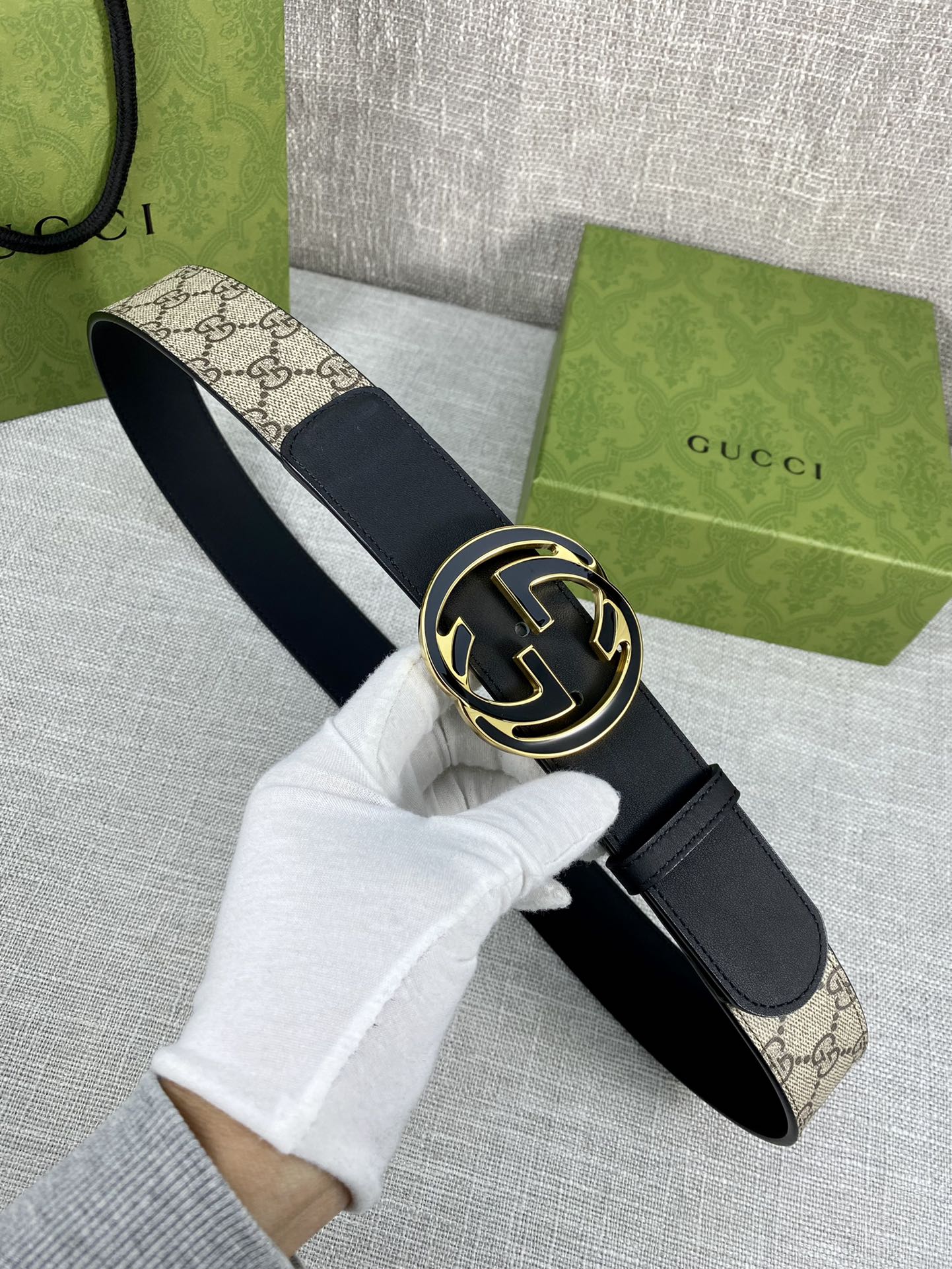 Gucci belt with dark strap and round GG logo buckle, worn end and clasp shown