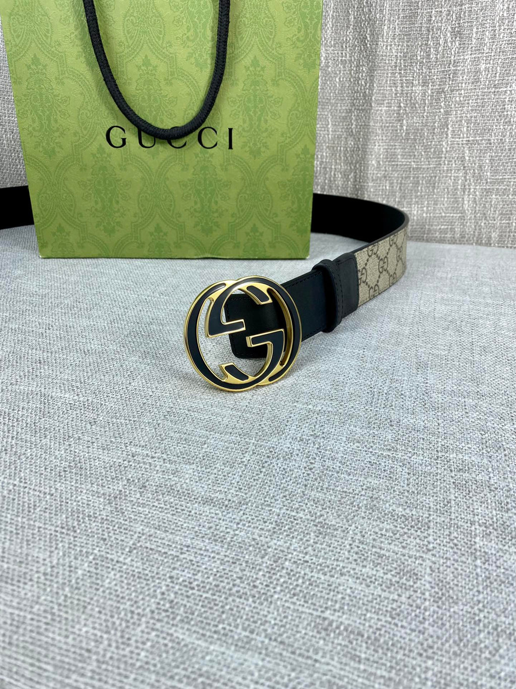 Gucci belt with dark strap and round GG logo buckle, flat on surface