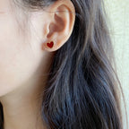 Heart stud earrings with red enamel and gold-tone crystal bezel, worn on ear