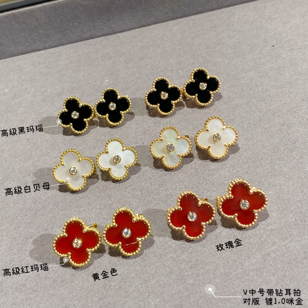 Clover-shaped stud earrings set with gold-tone outlines in black, white, and red
